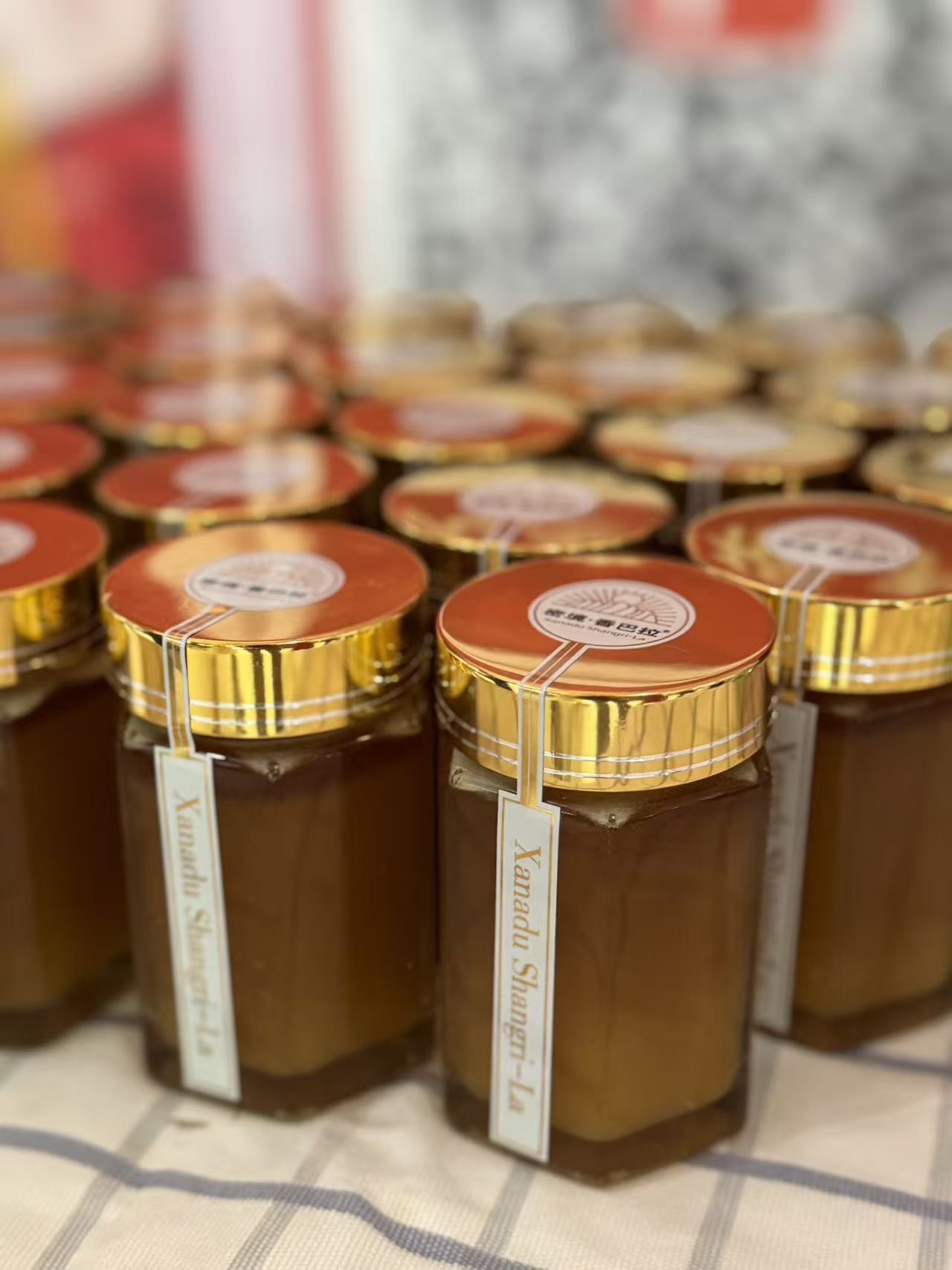 Close-up of Xanadu Shangri-La honey jars with gold lids on the booth table